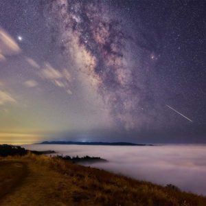 Galaxy of stars over fog on a cliff