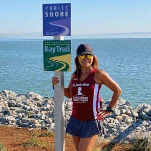 Woman in athletic wear standing next to Bay Trail sign