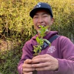 Person smiling while holding a small plant