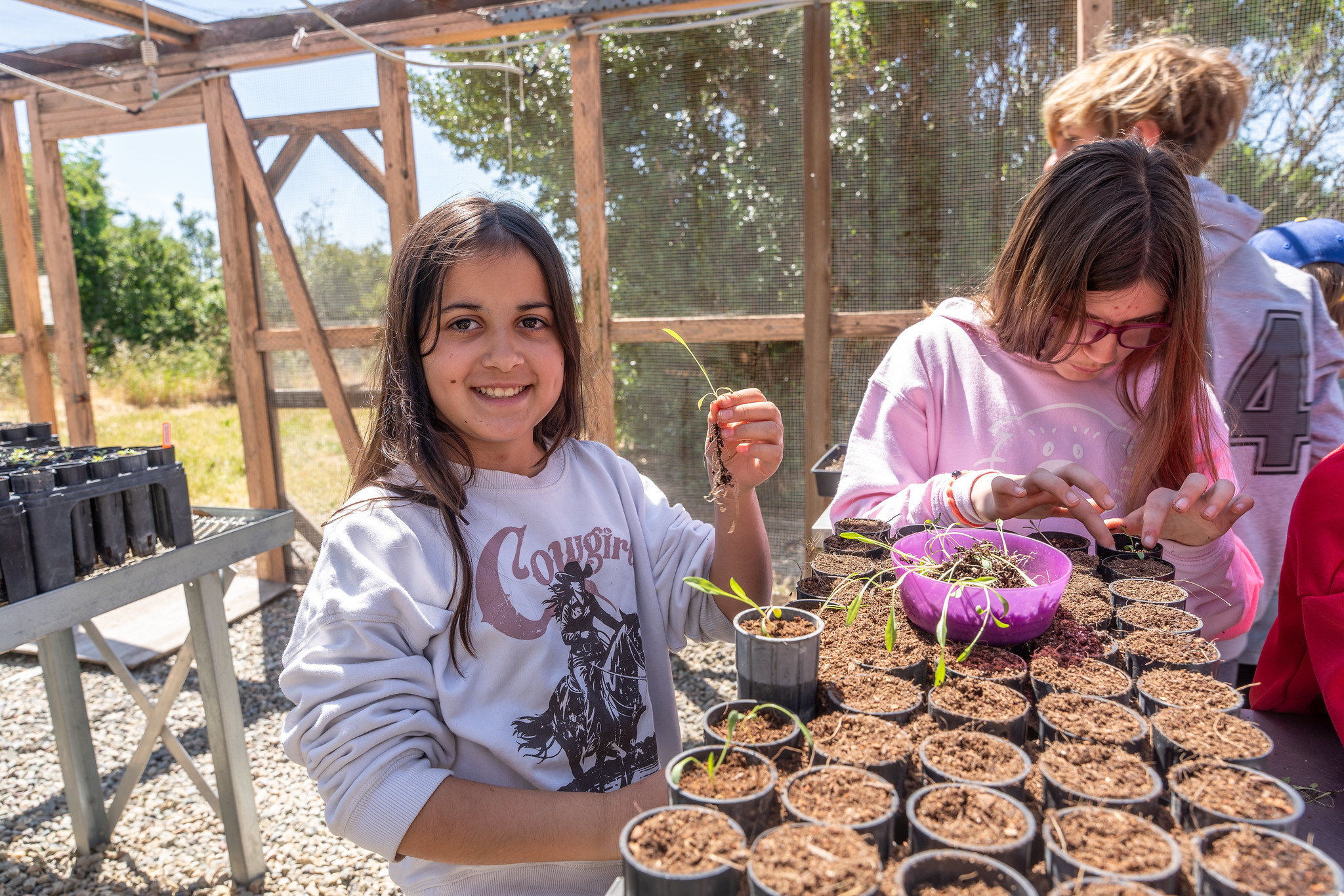 Child smiling while planting a seedling in a pot