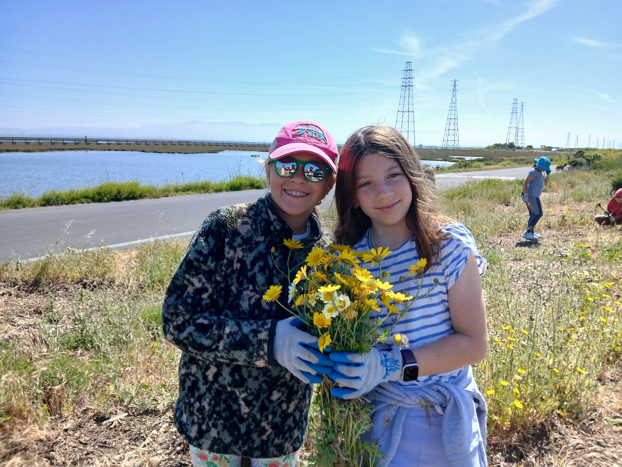 Two girls smiling holding plants in front of the Bay