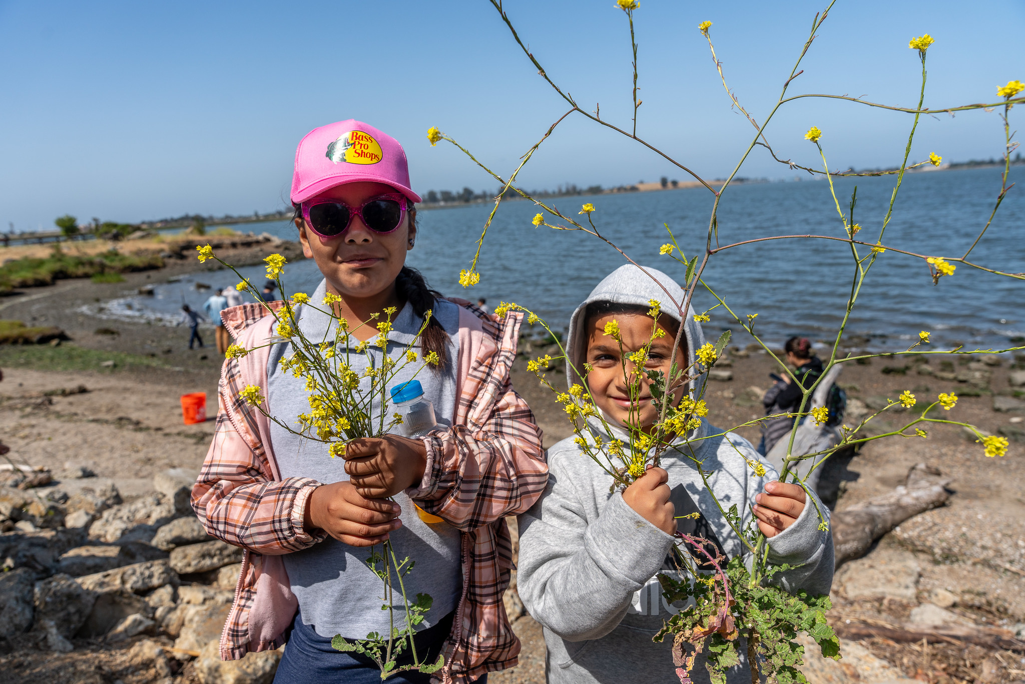 Children smiling holding plants in front of the Bay