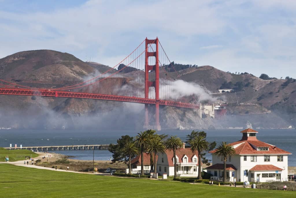 Golden Gate bridge behind a green field and buildings